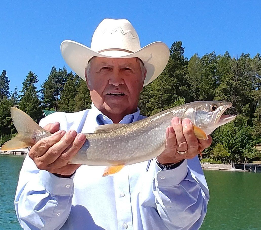A man in a cowboy hat is holding a fish in his hands