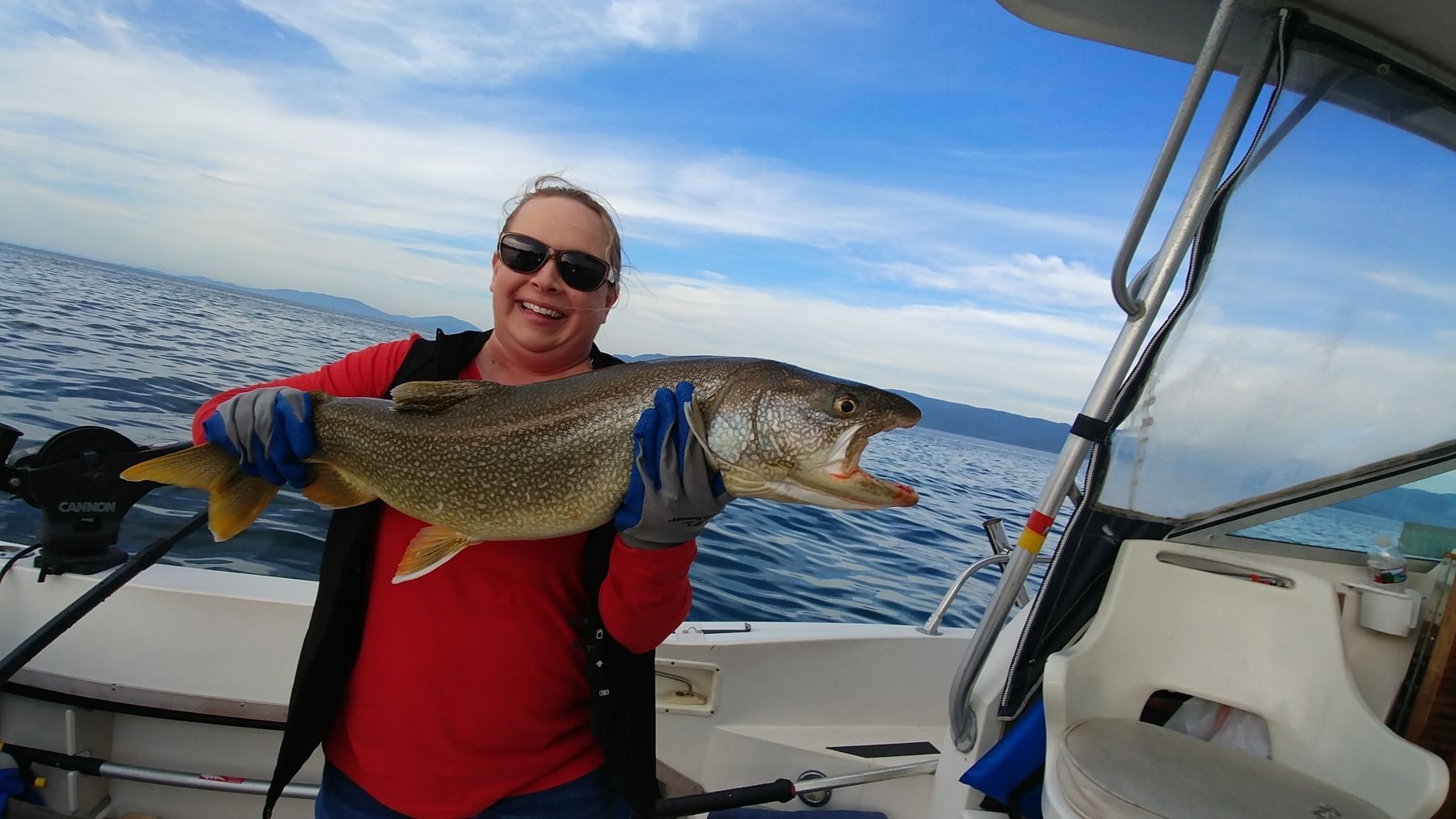 A woman is holding a large fish on a boat.