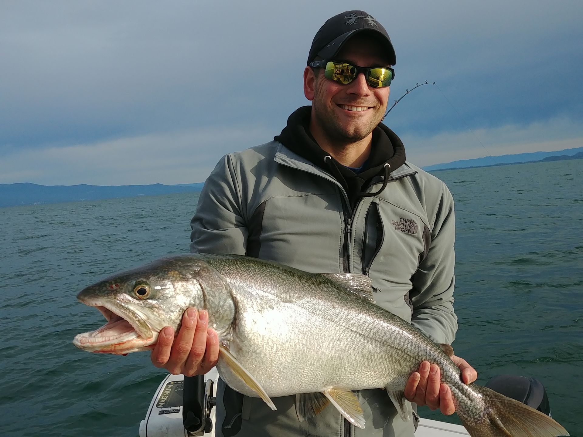 A man is holding a large fish in his hands on a boat.