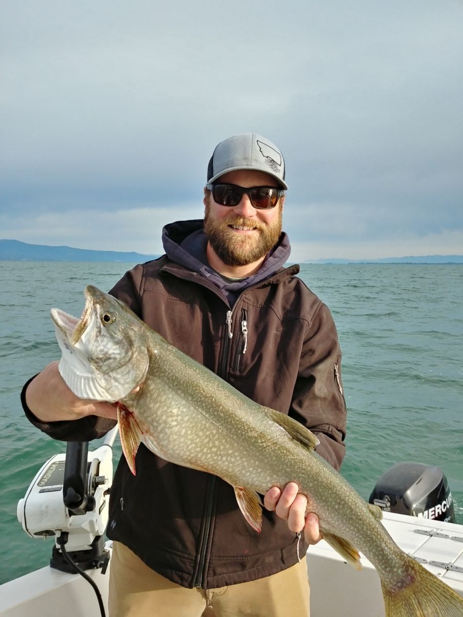 A man is holding a large fish on a boat.