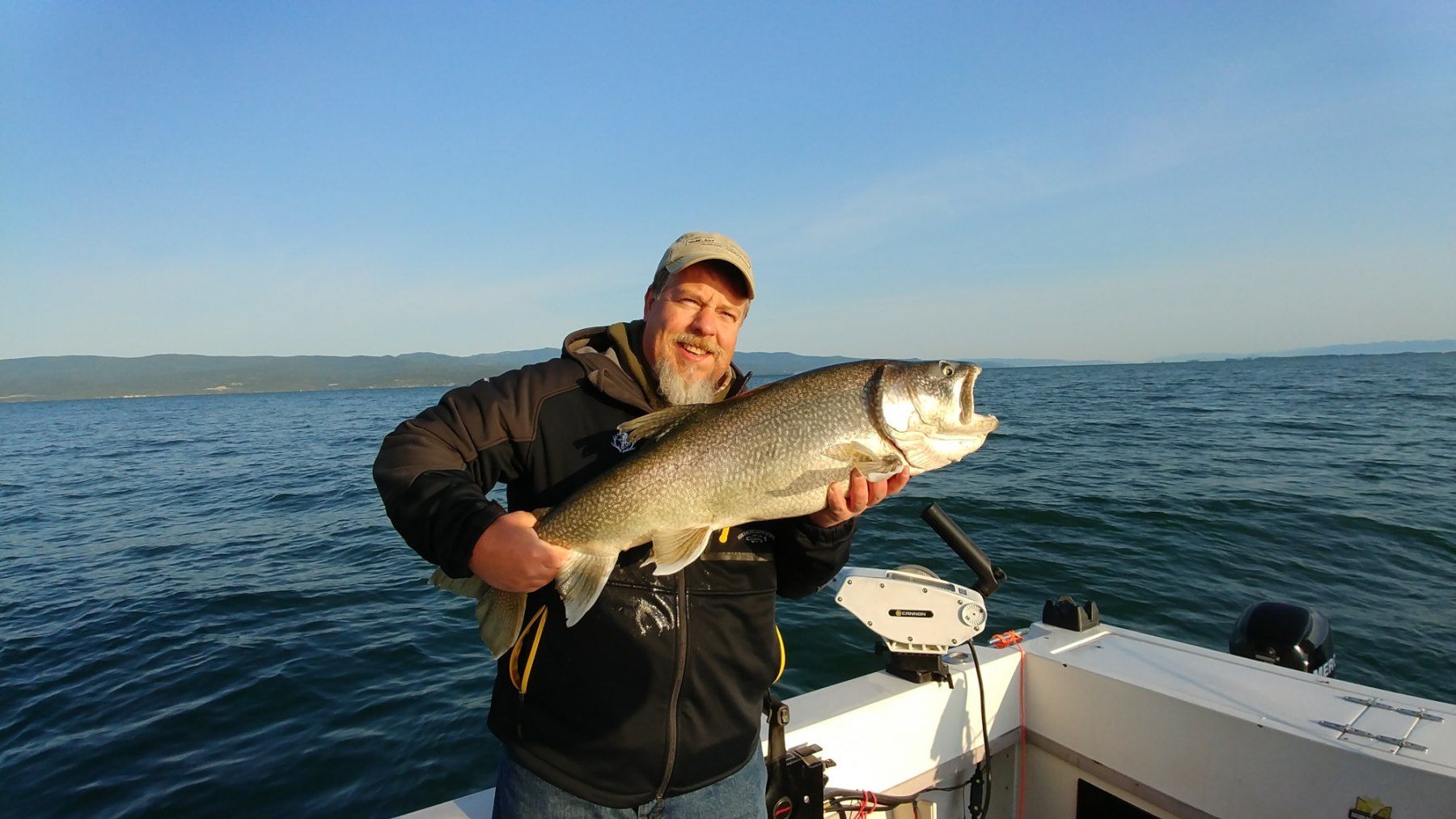 A man is holding a large fish on a boat in the water.
