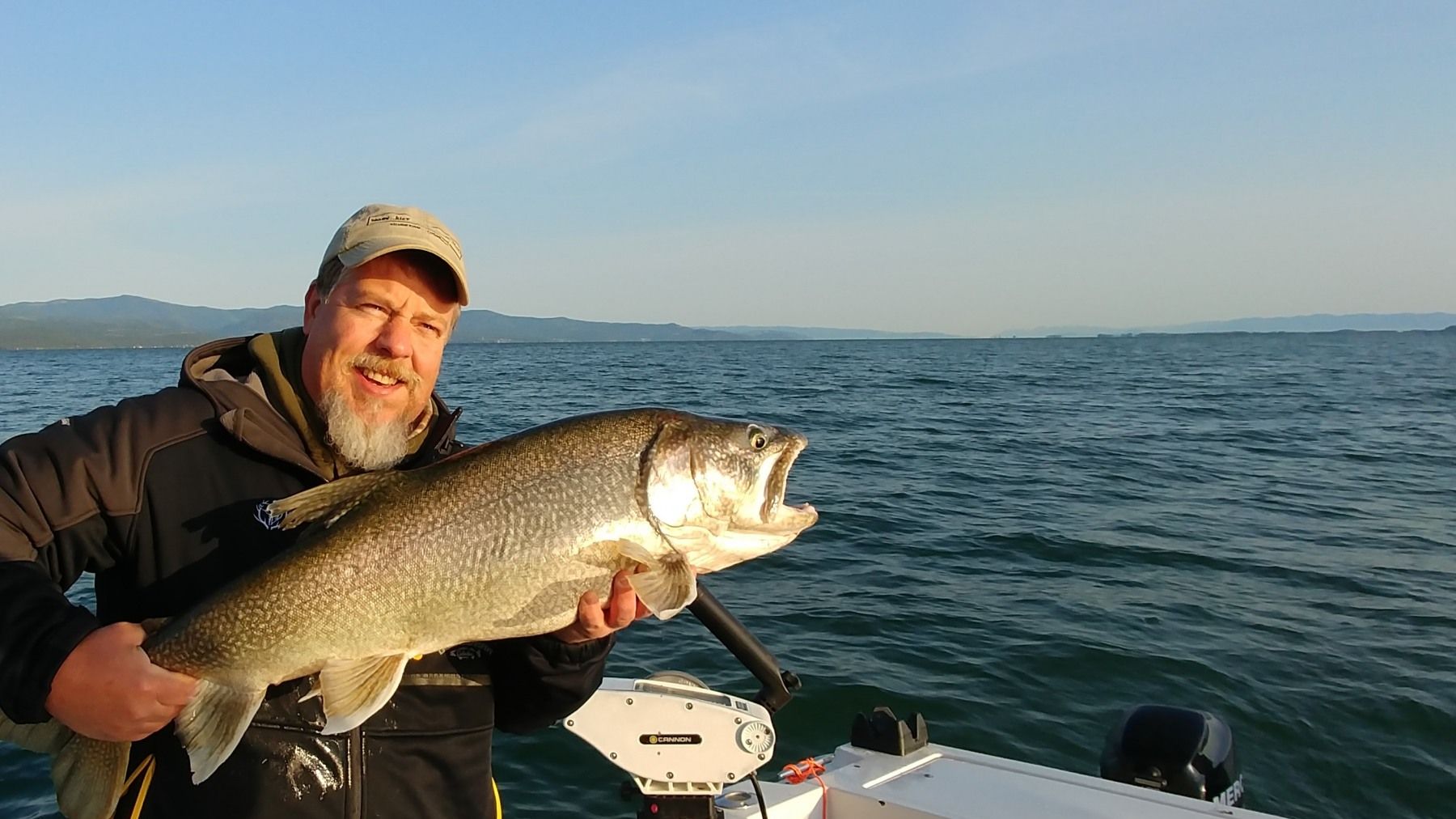 A man is holding a large fish on a boat in the water.