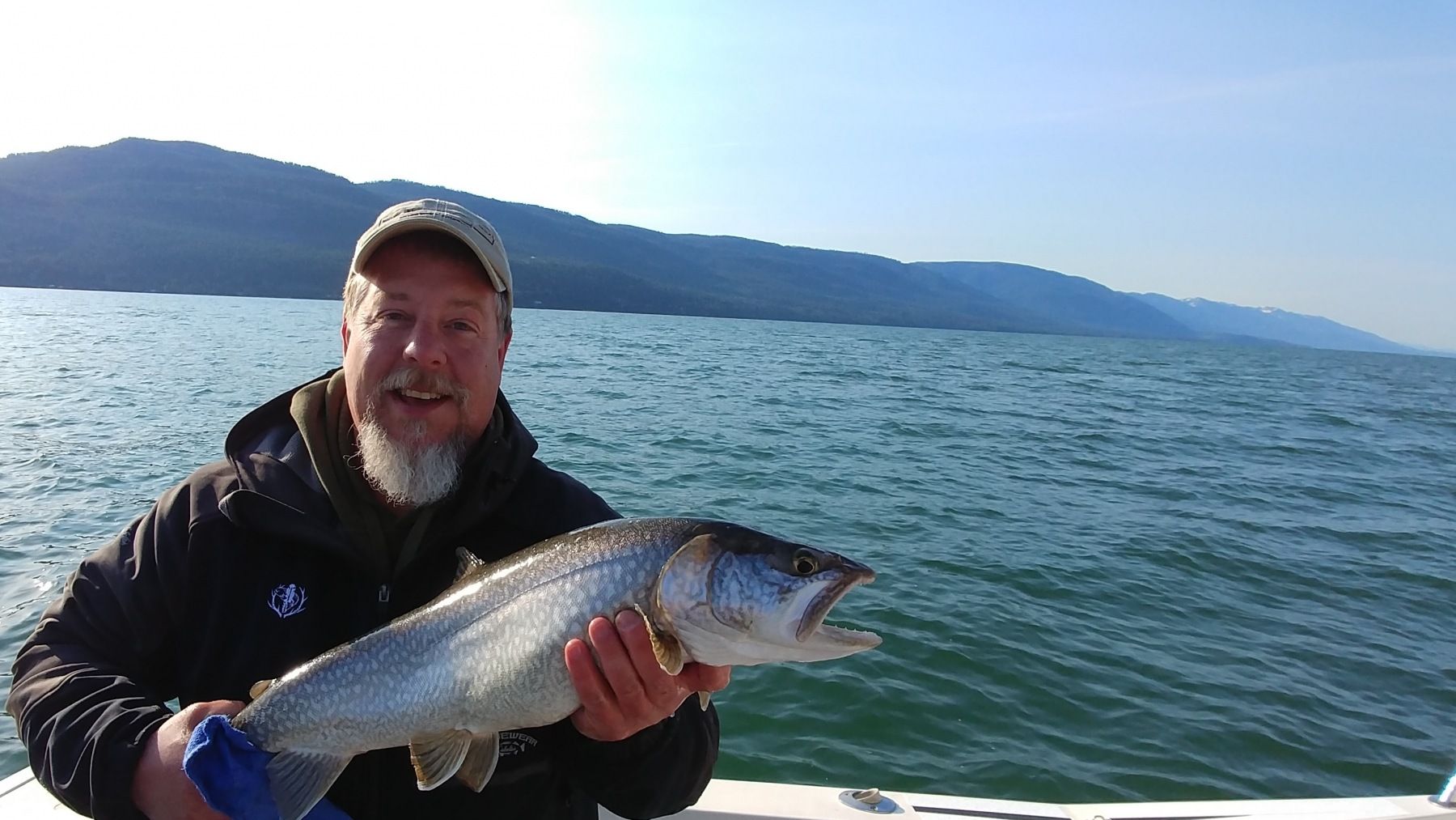 A man is holding a fish on a boat in the water.
