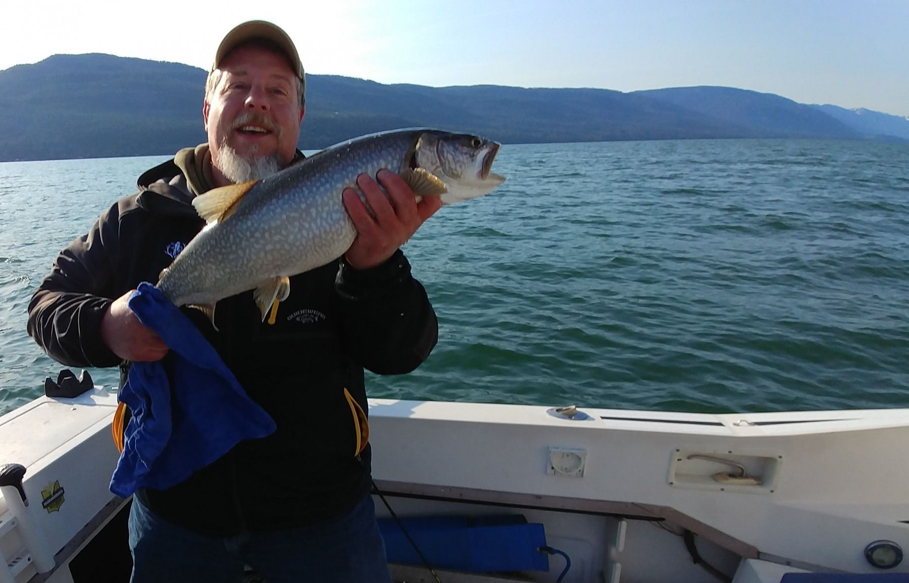 A man is holding a fish on a boat in the water