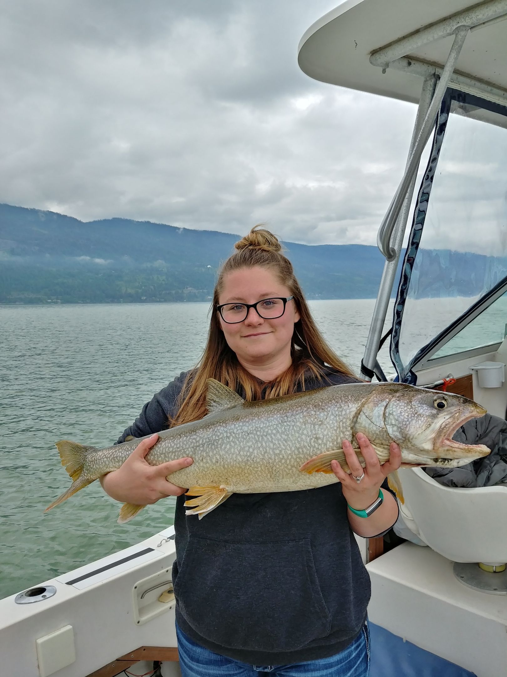 A woman is holding a large fish on a boat.