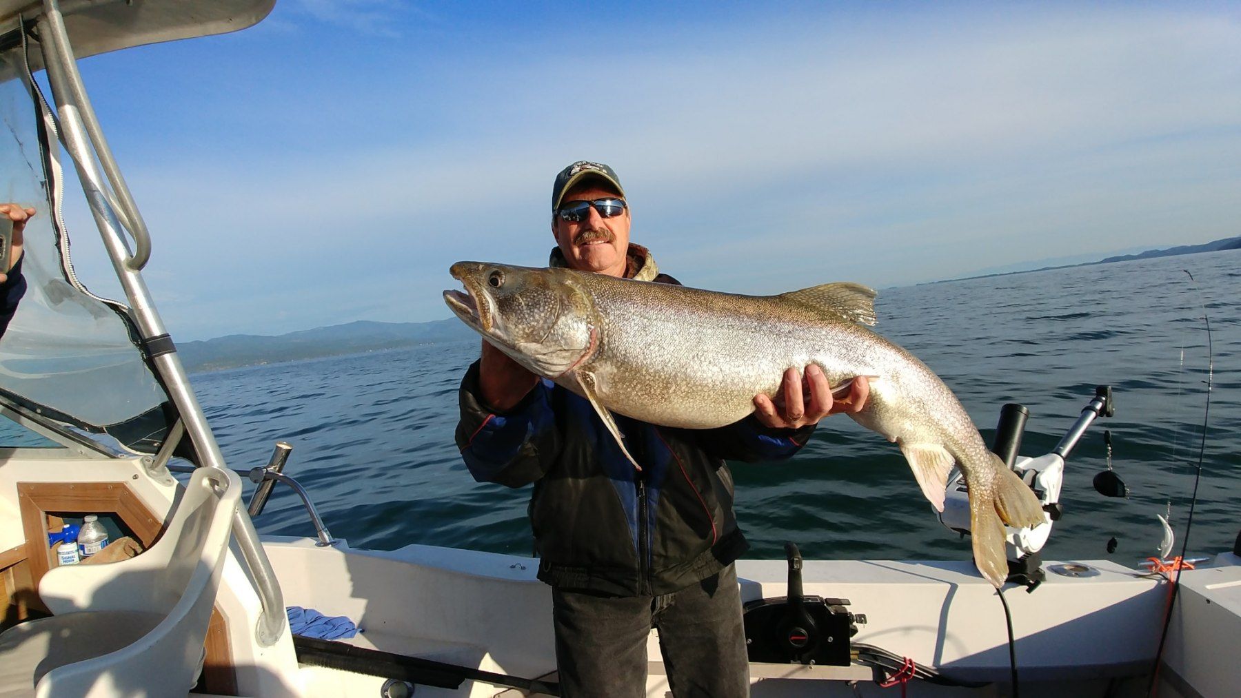 A man is holding a large fish on a boat.