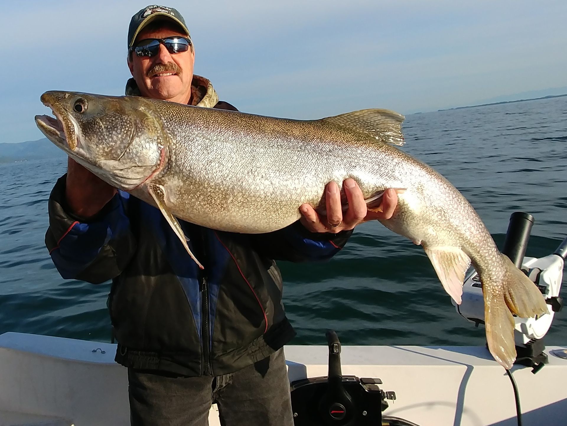 A man on a boat holding a large fish