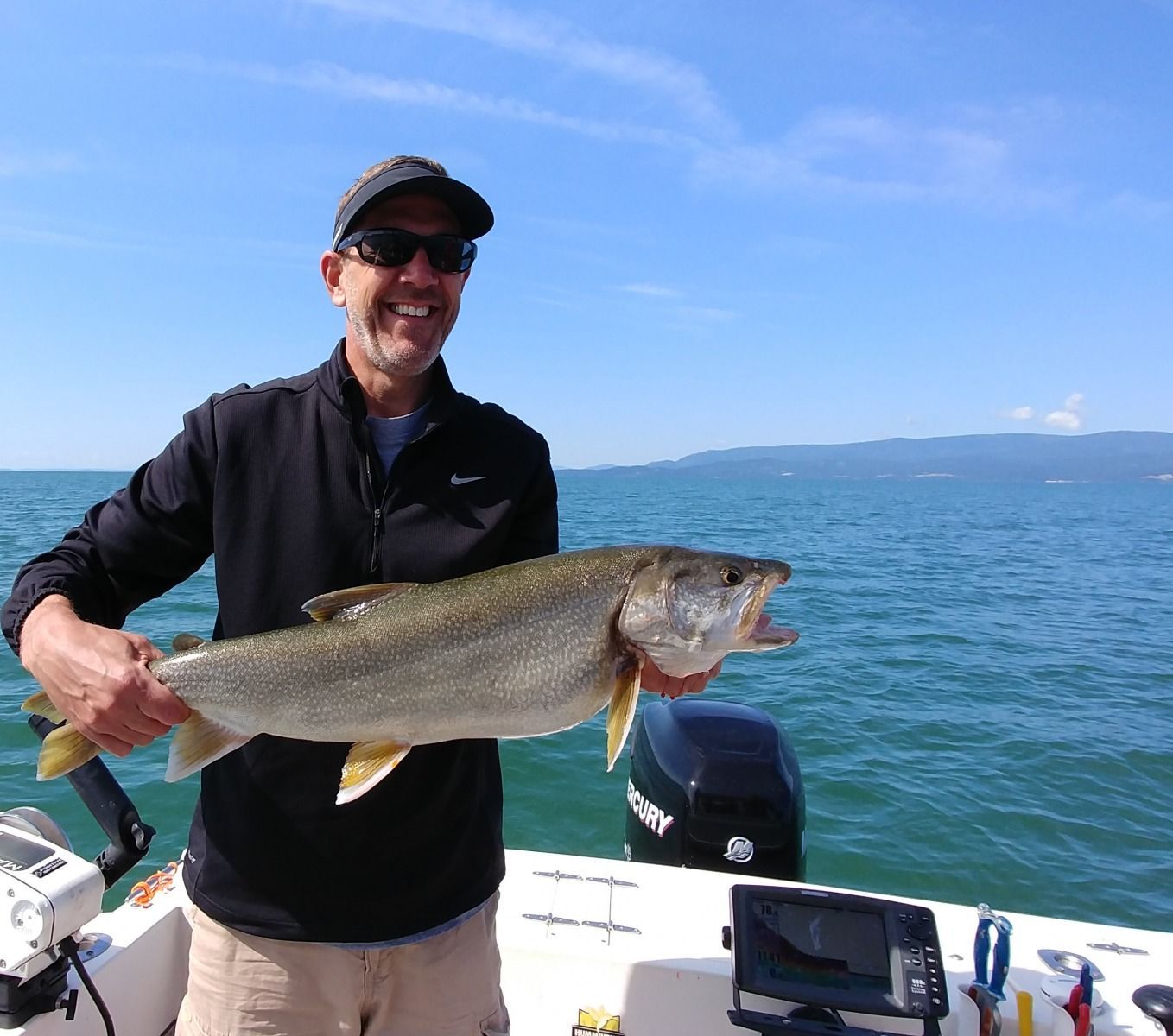 A man is holding a large fish on a boat.