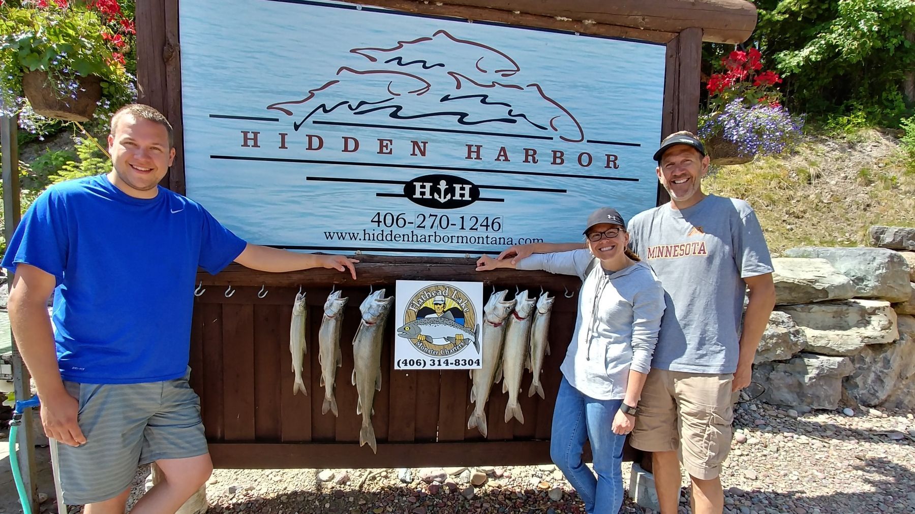 Three people standing in front of a sign that says hidden harbor