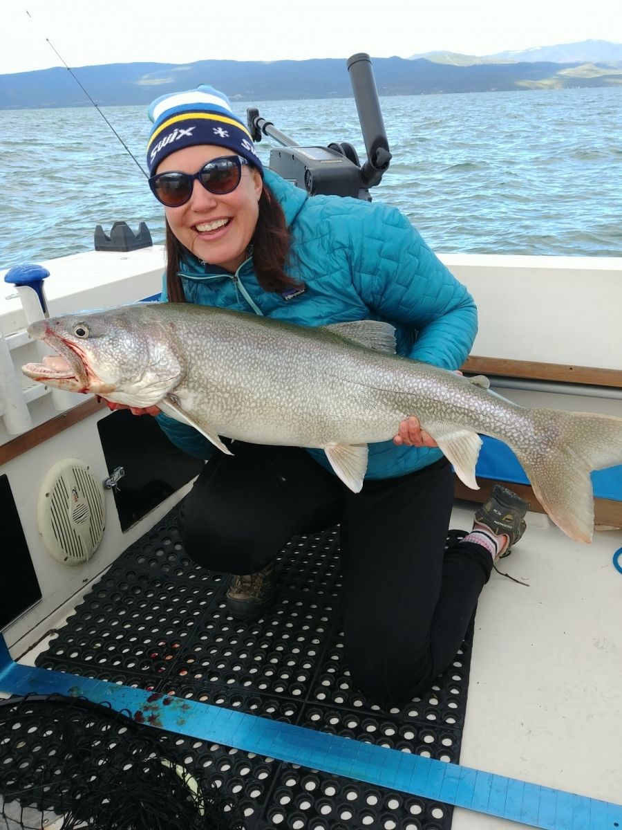 A woman is kneeling on a boat holding a large fish