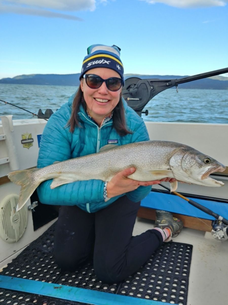 A woman is kneeling on a boat holding a large fish.