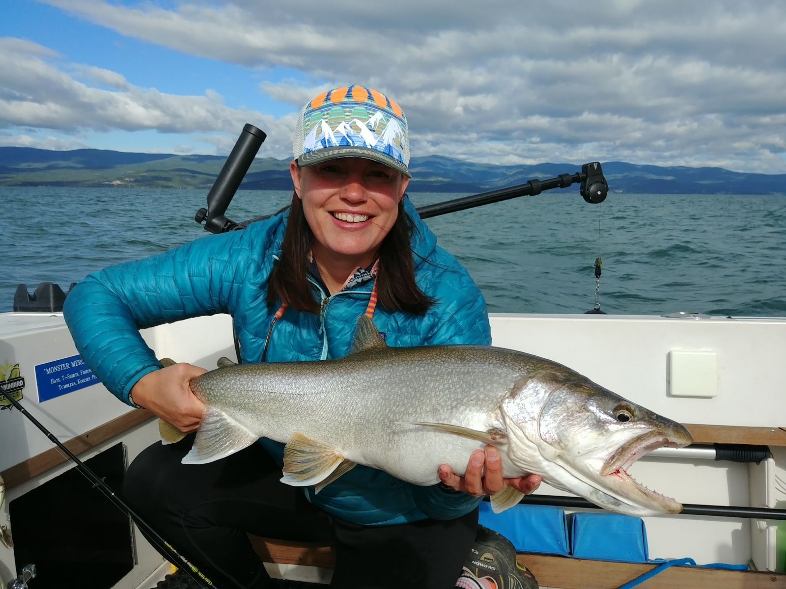 A woman is holding a large fish on a boat