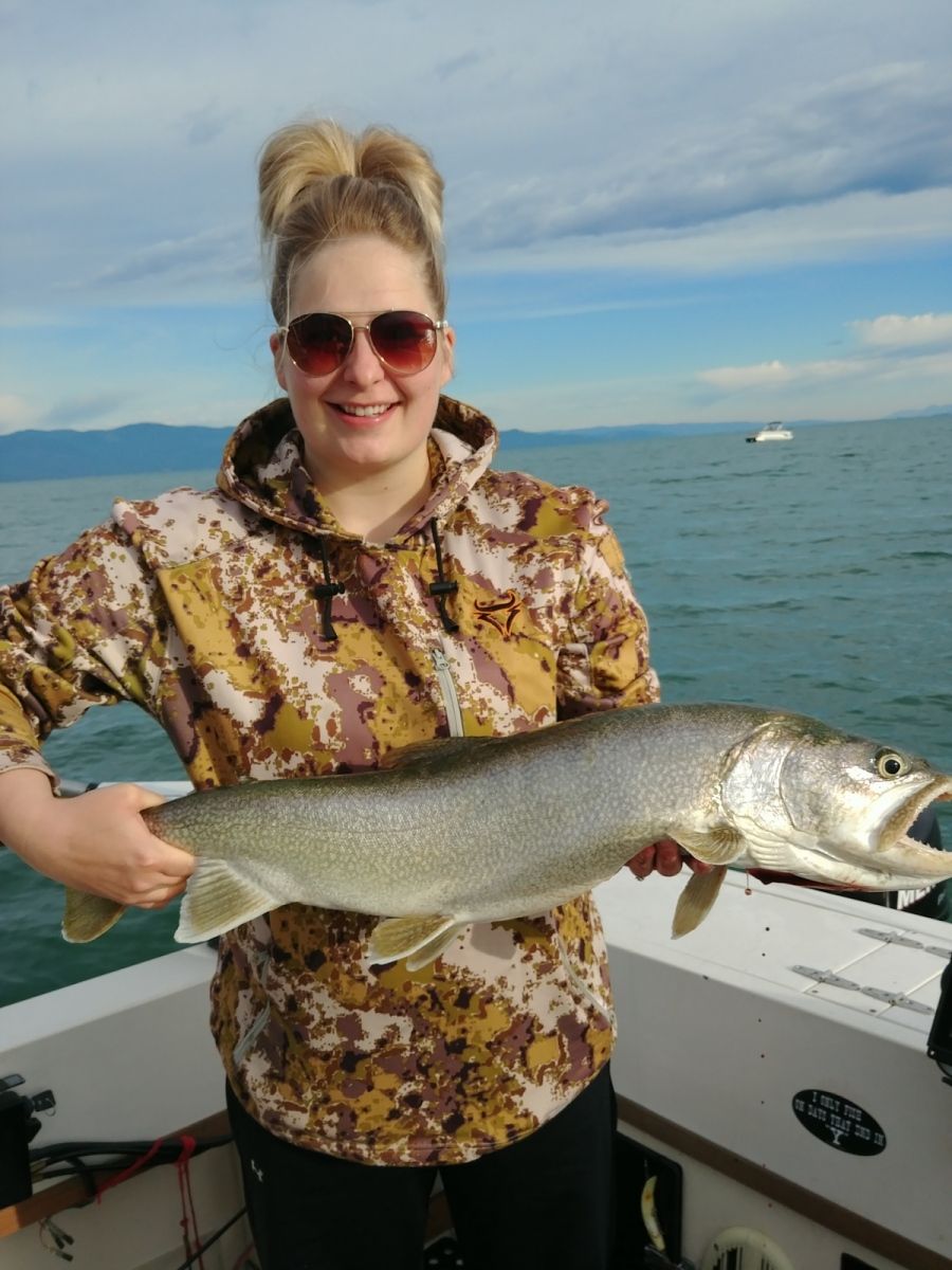 A woman is holding a large fish on a boat.