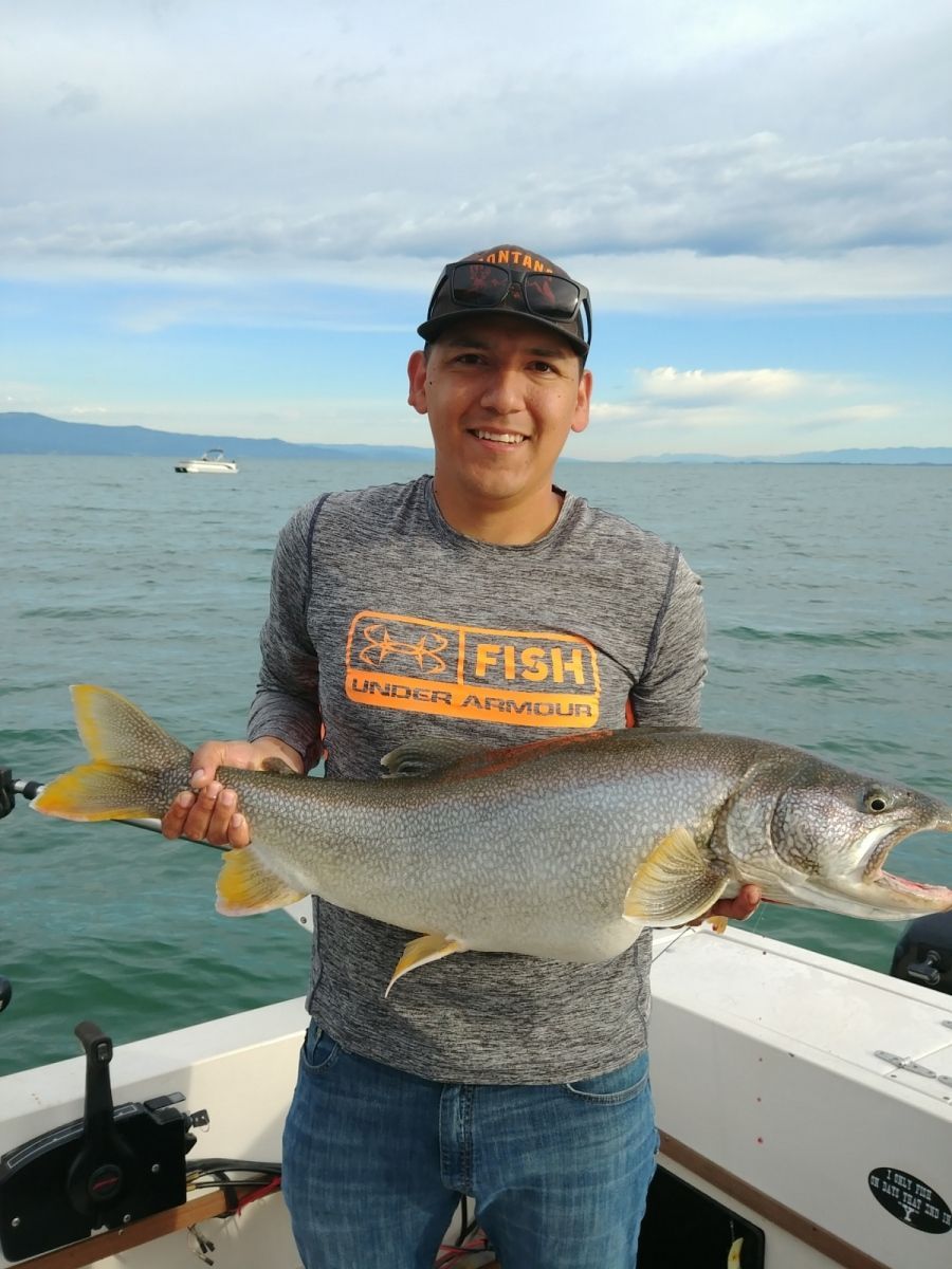 A man is holding a large fish on a boat.