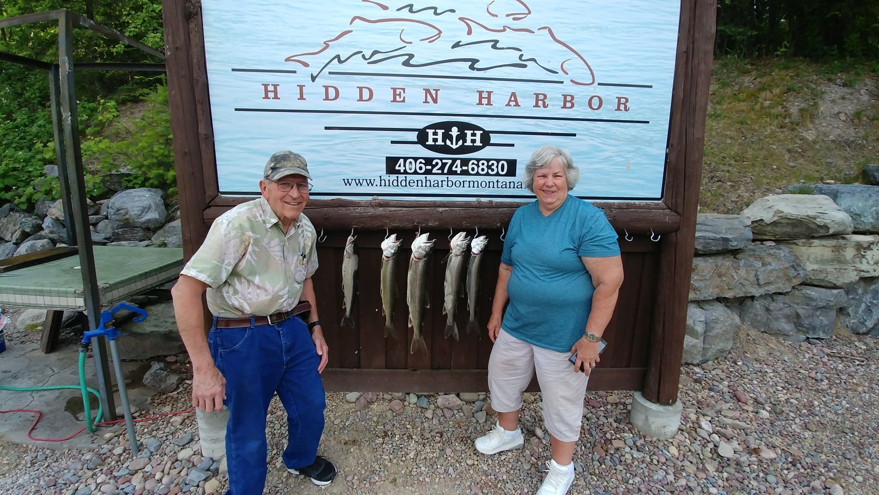 A man and a woman are standing in front of a sign that says hidden harbor.