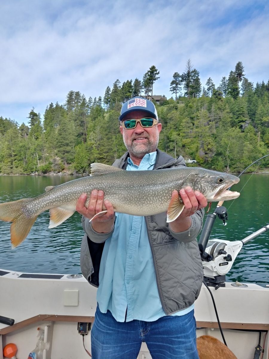 A man is holding a large fish in his hands on a boat.