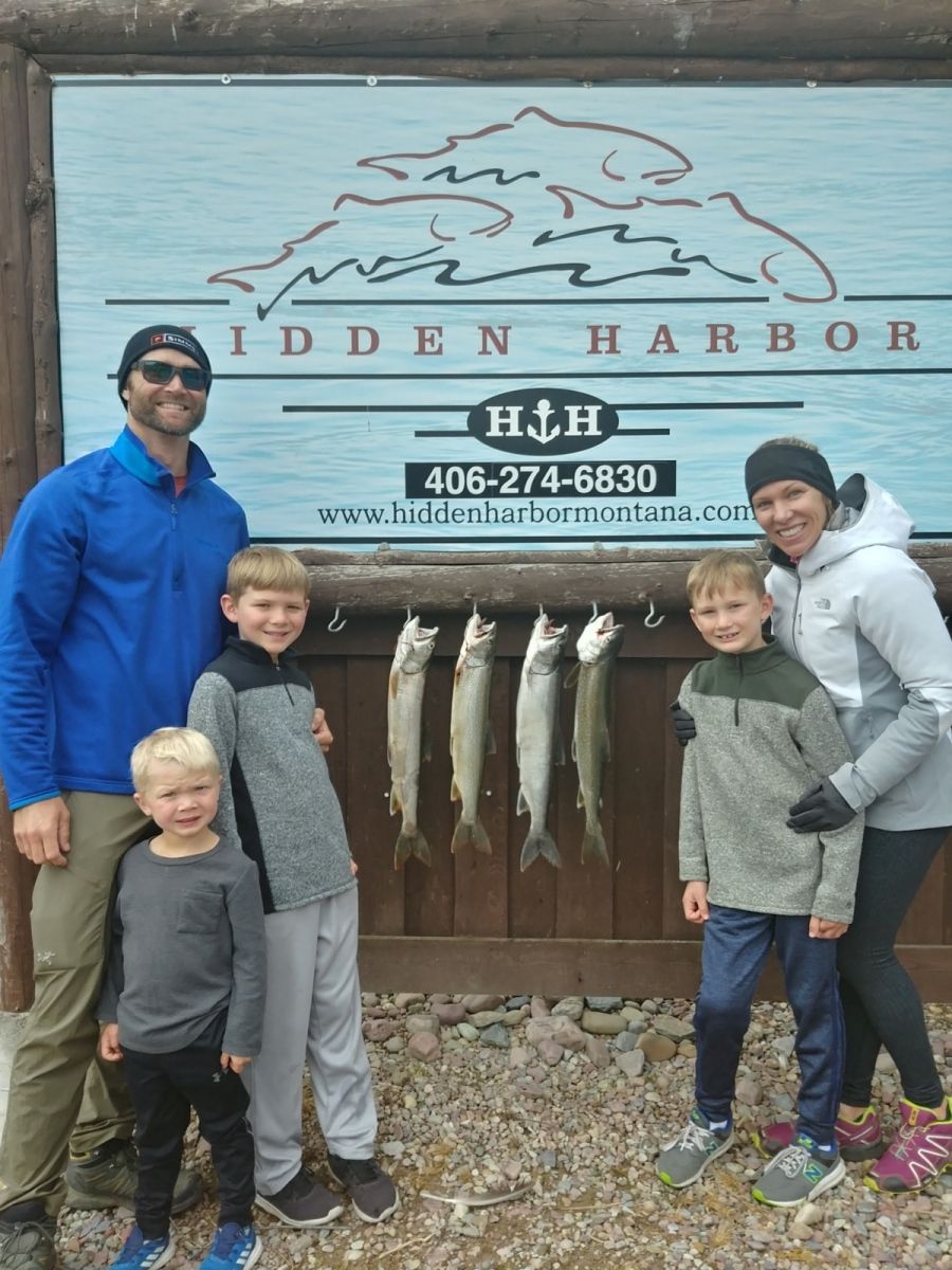 A family is posing for a picture in front of a sign that says hidden harbor.