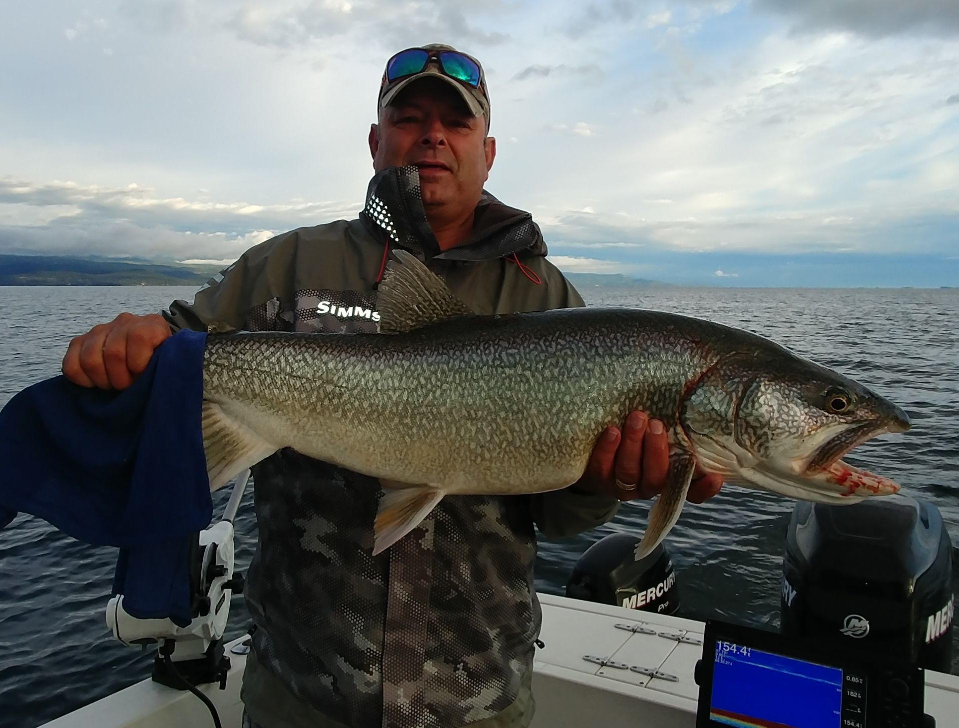 A man is holding a large fish on a boat