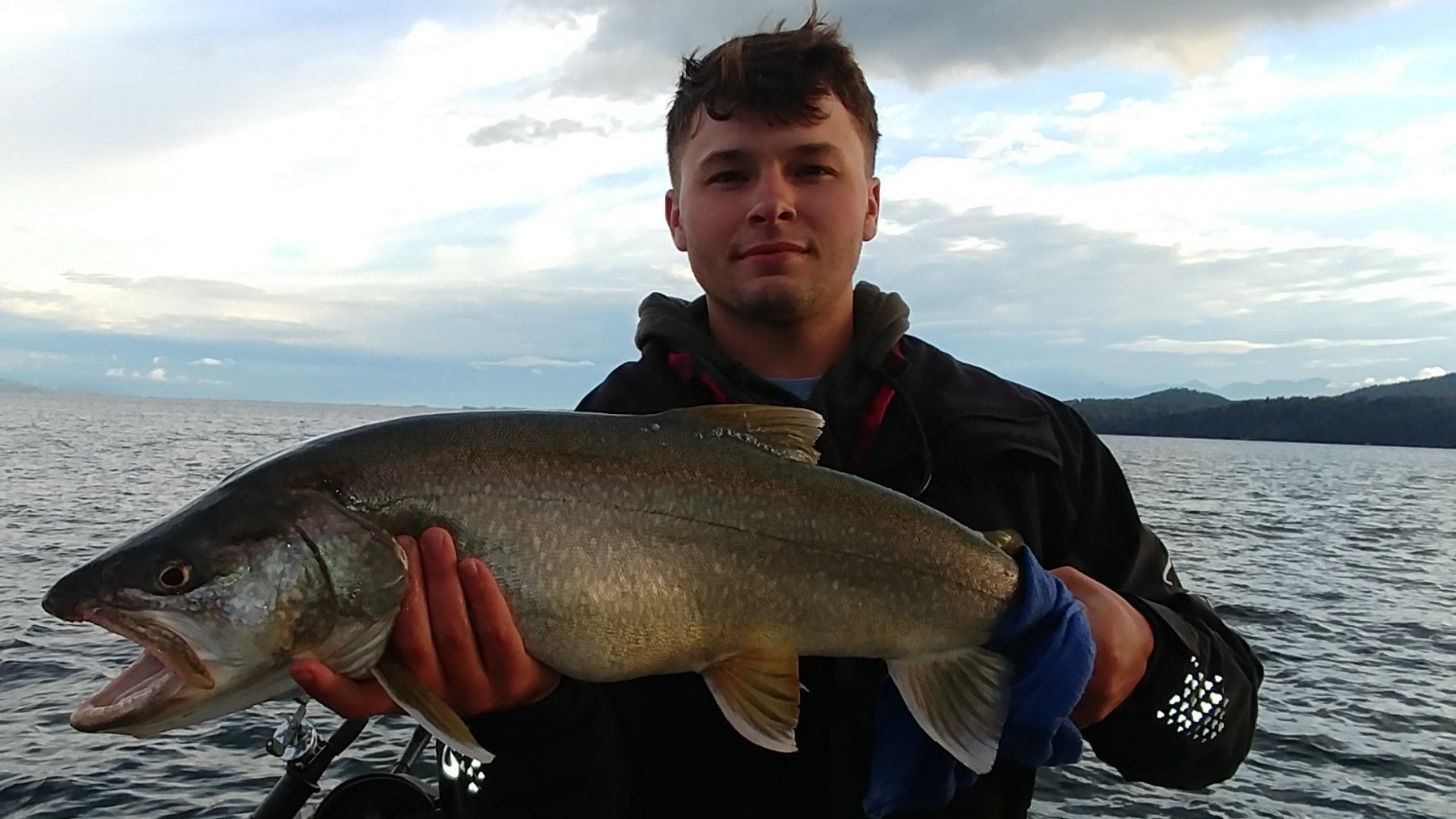 A young man is holding a large fish in his hands.