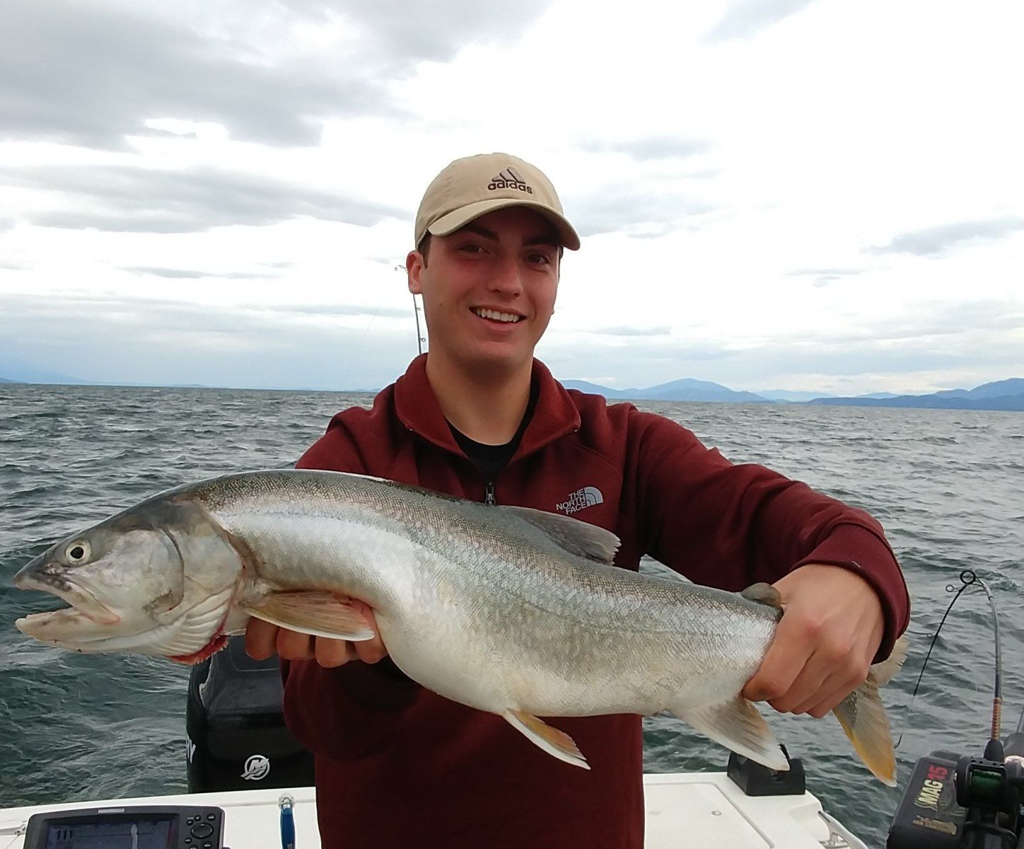 A man is holding a large fish on a boat