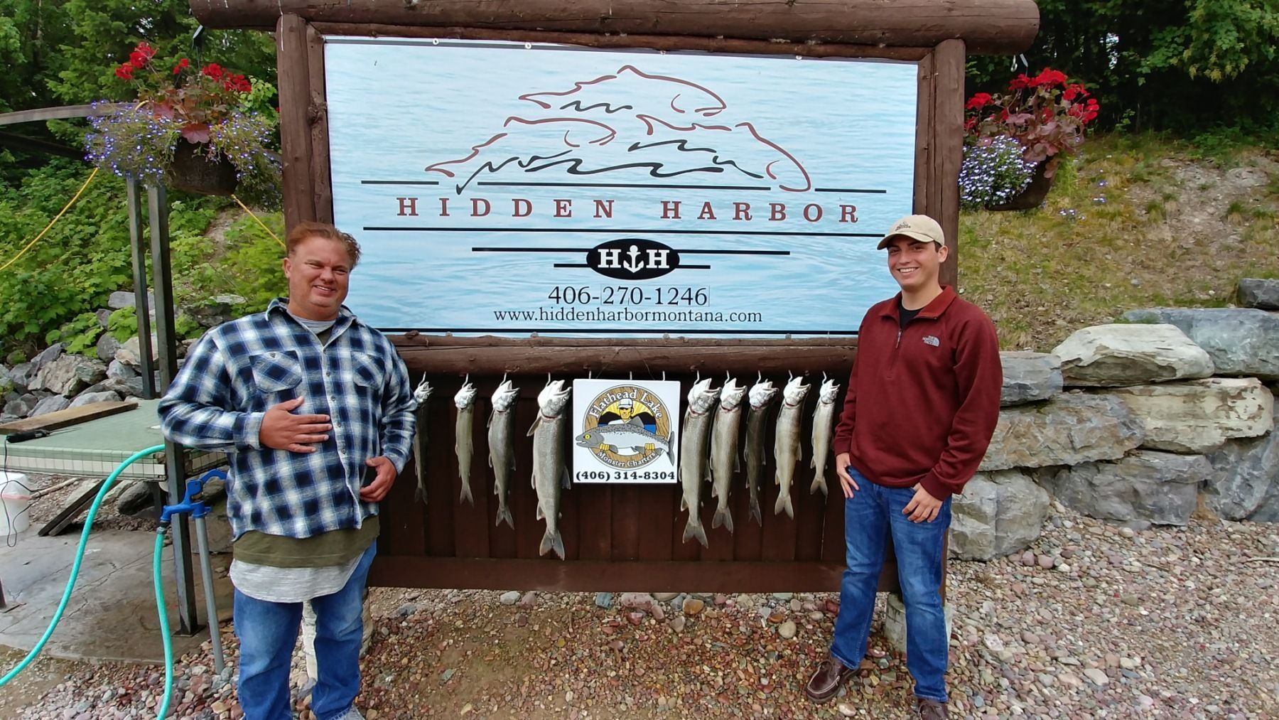 Two men are standing in front of a sign with fish on it.
