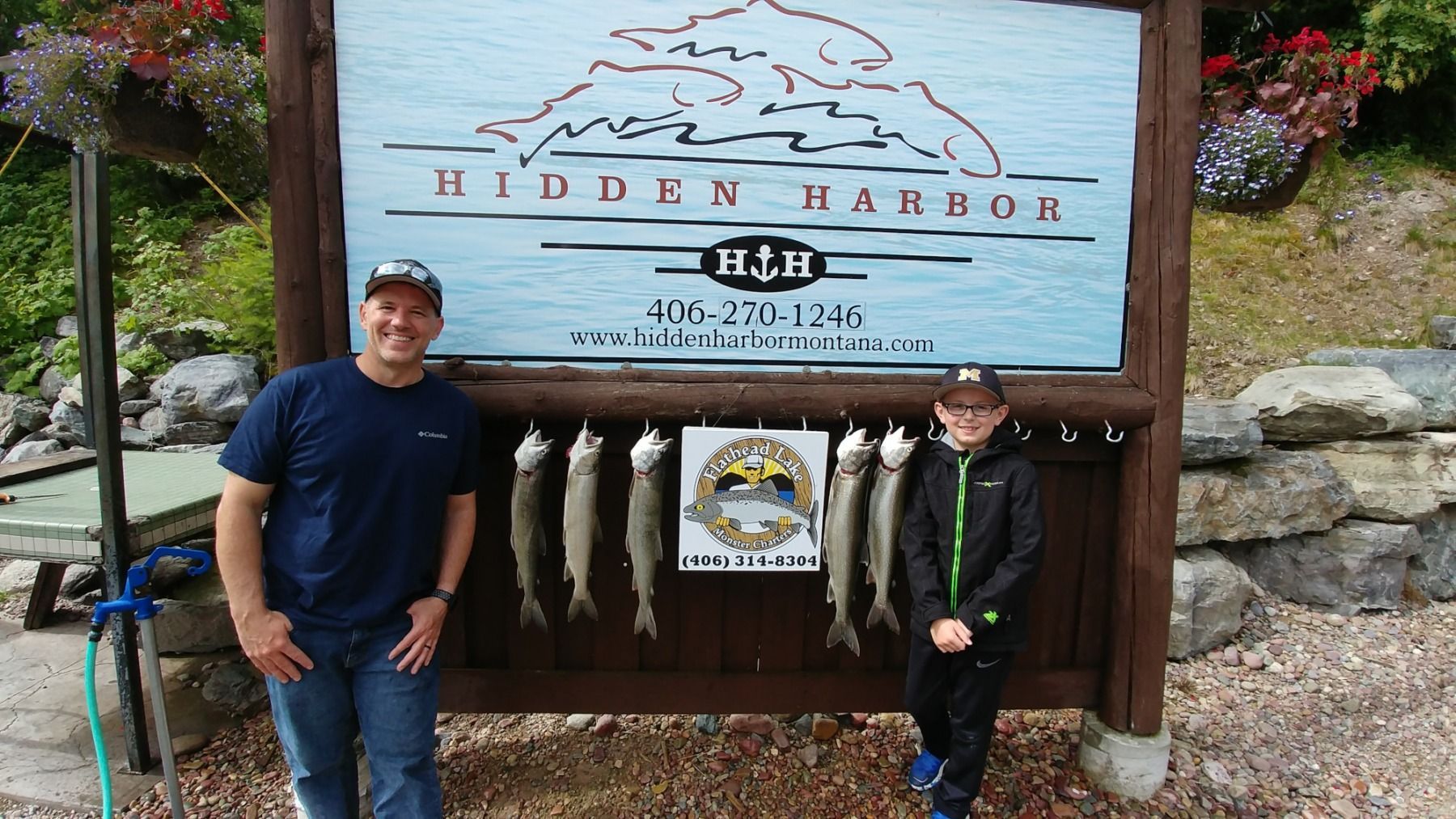 Two men standing in front of a sign that says hidden harbor