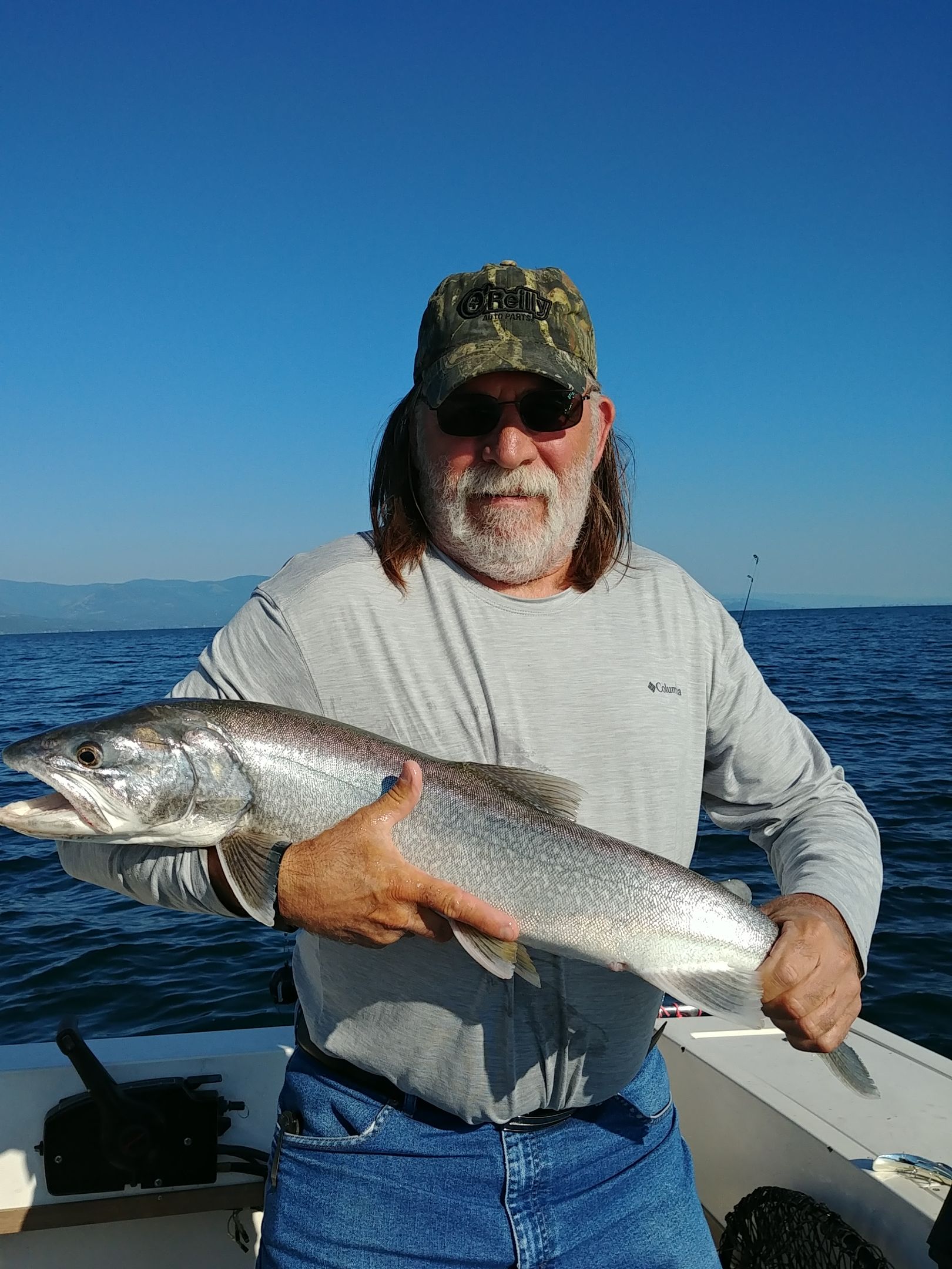 A man is holding a large fish on a boat in the ocean.