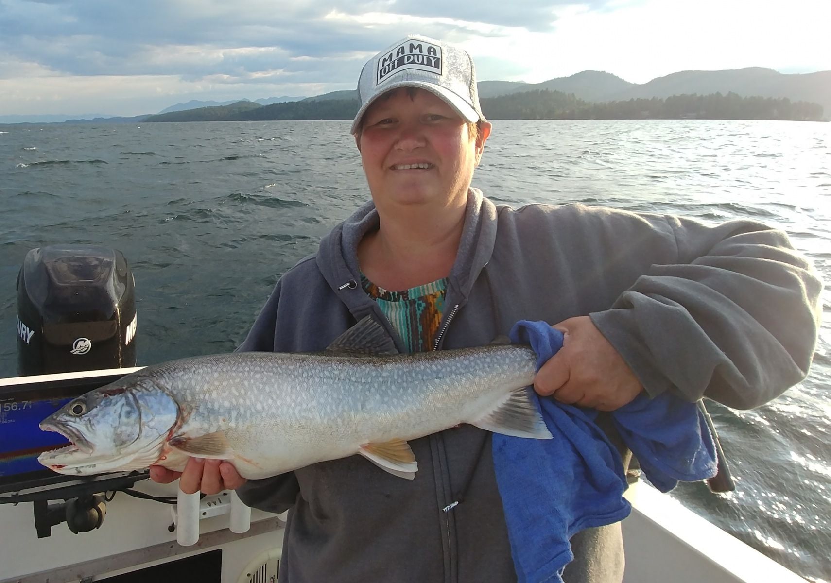 A woman is holding a large fish on a boat