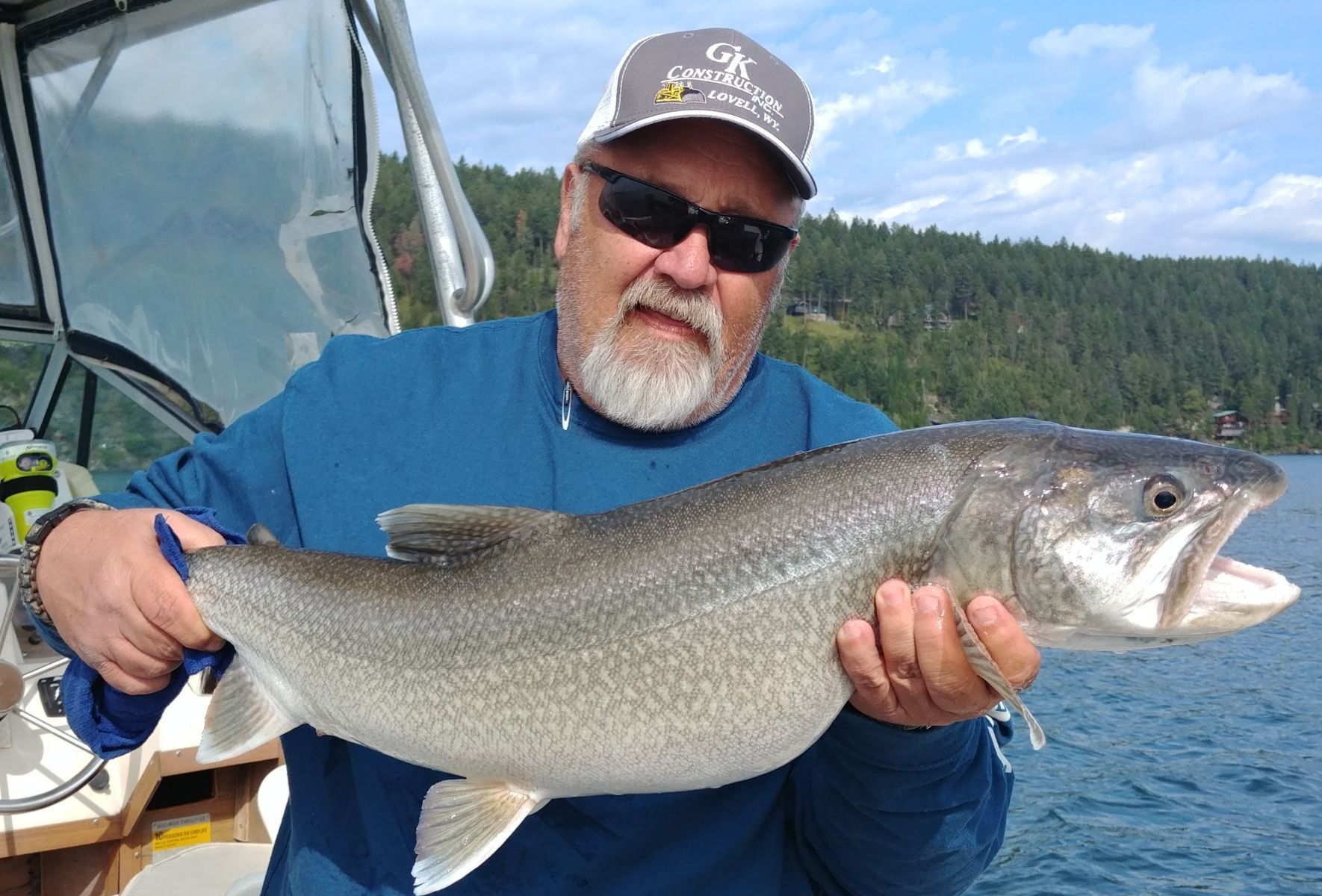 A man is holding a large fish in his hands on a boat.