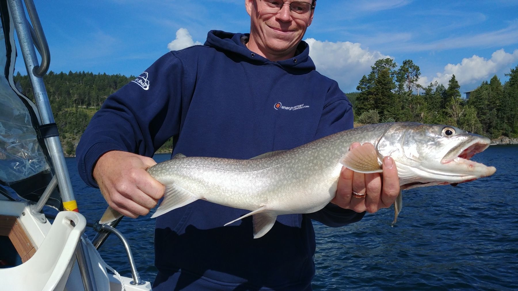 A man is holding a large fish in his hands on a boat.