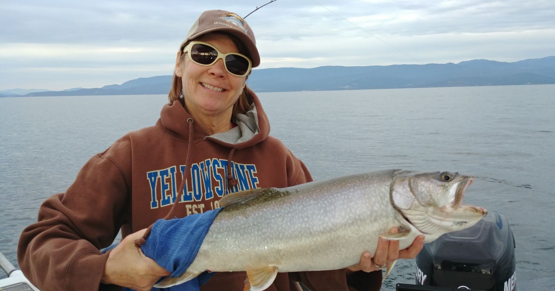 A woman is holding a large fish on a boat.