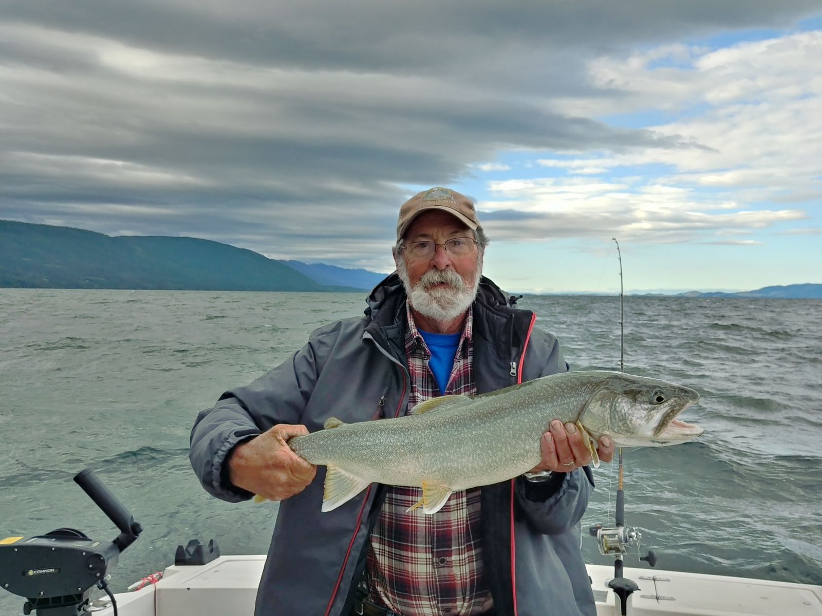 A man is holding a large fish on a boat in the water.