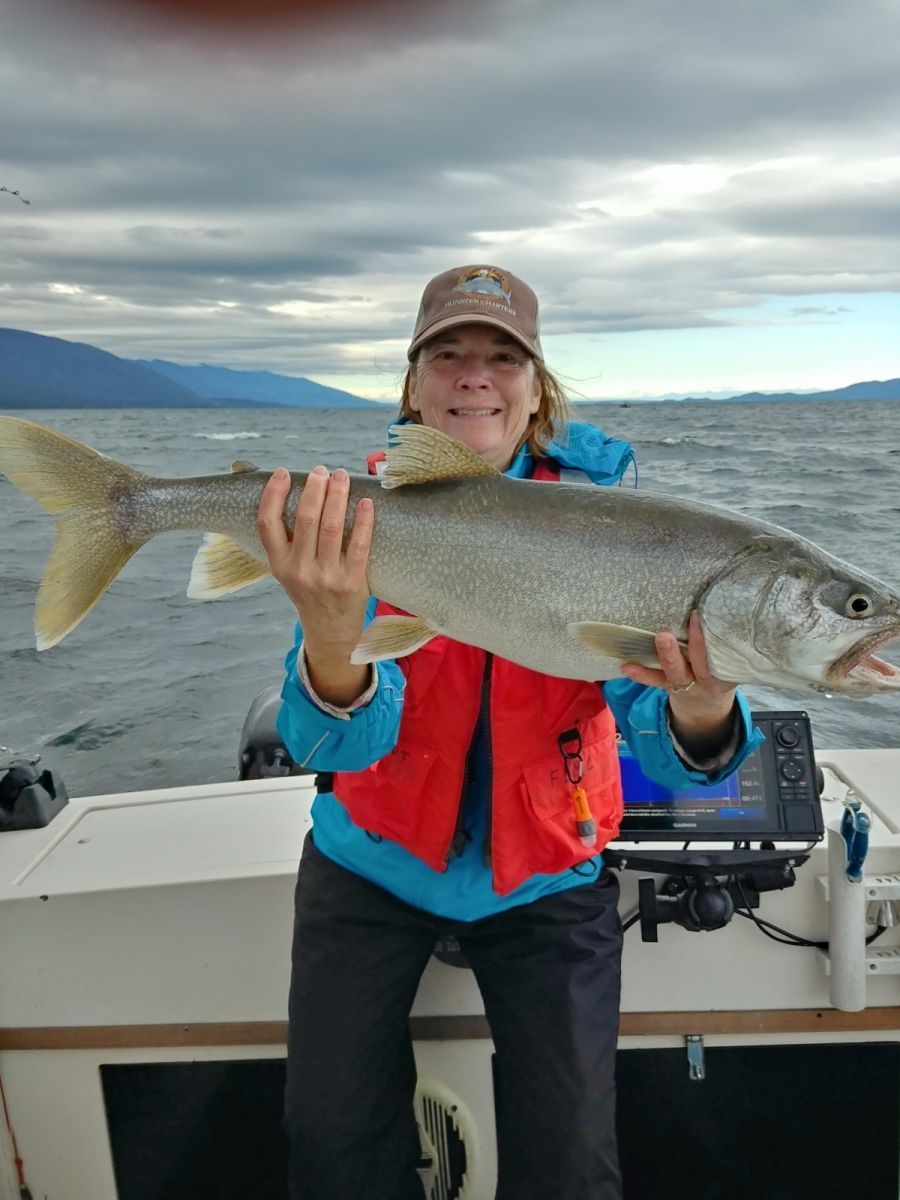 A woman is holding a large fish on a boat.