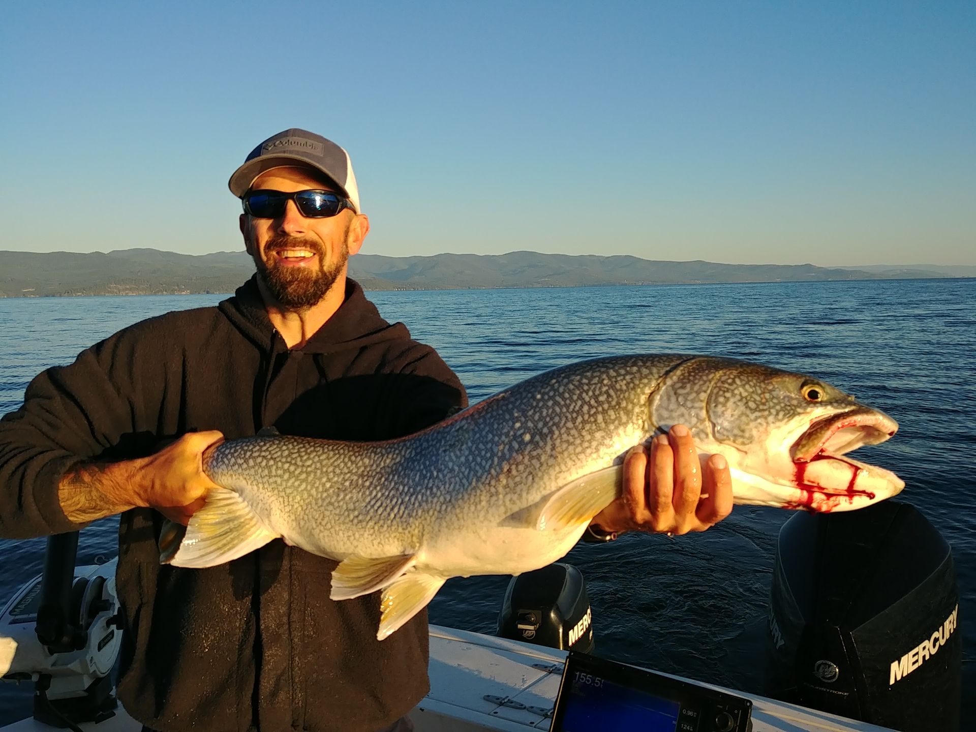 A man is holding a large fish in his hands on a boat.