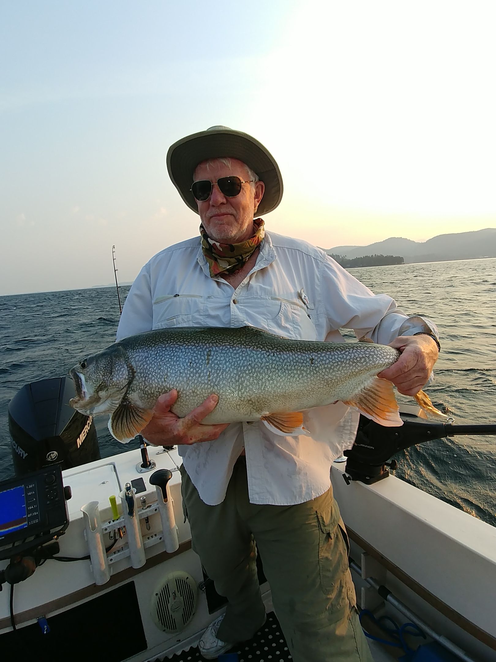 A man is holding a large fish on a boat.