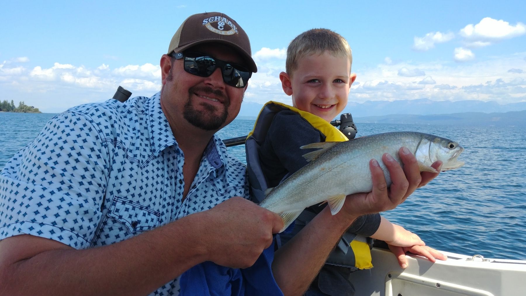 A man and a boy are holding a fish on a boat.