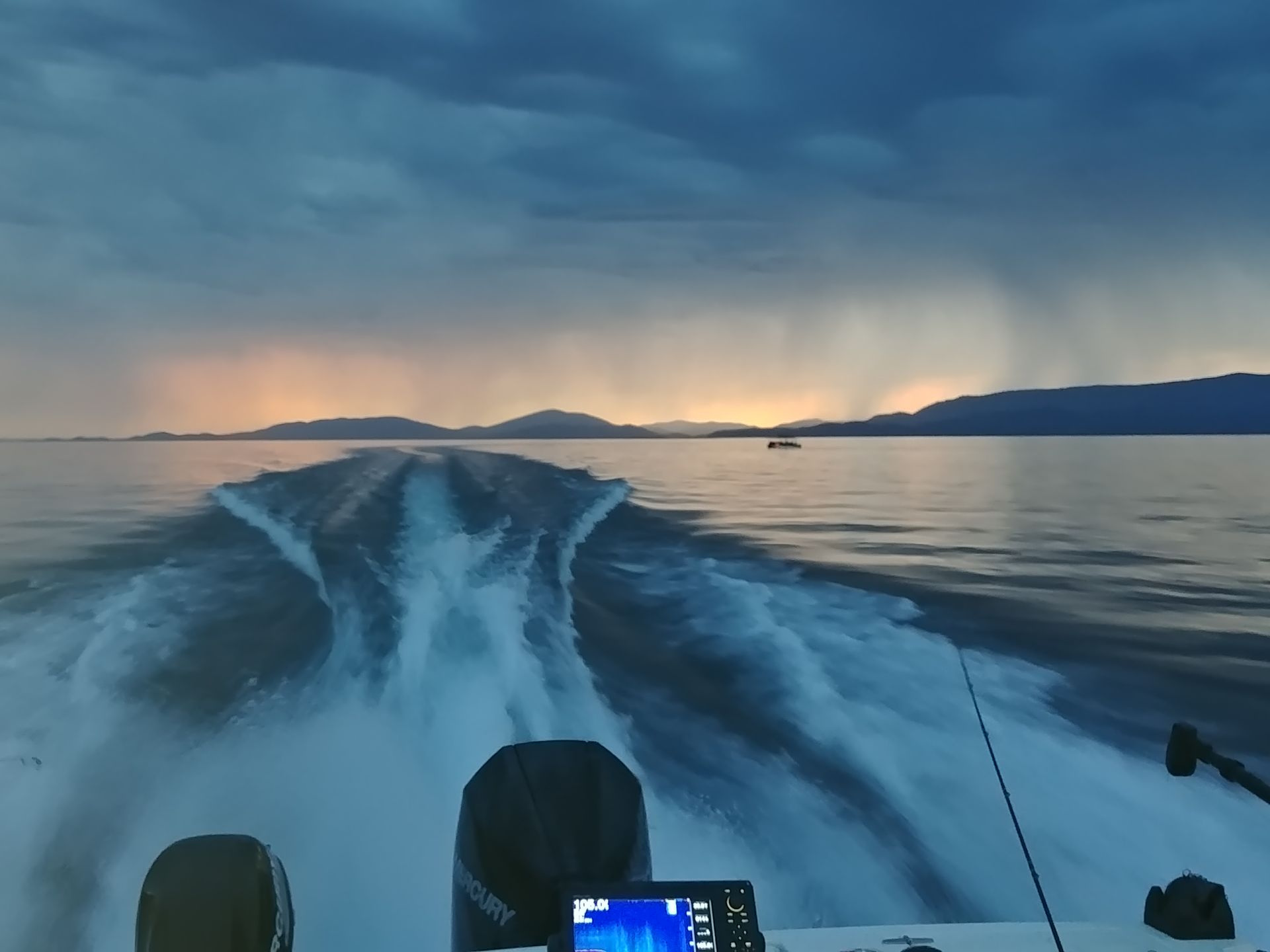 A boat is going through a body of water with mountains in the background