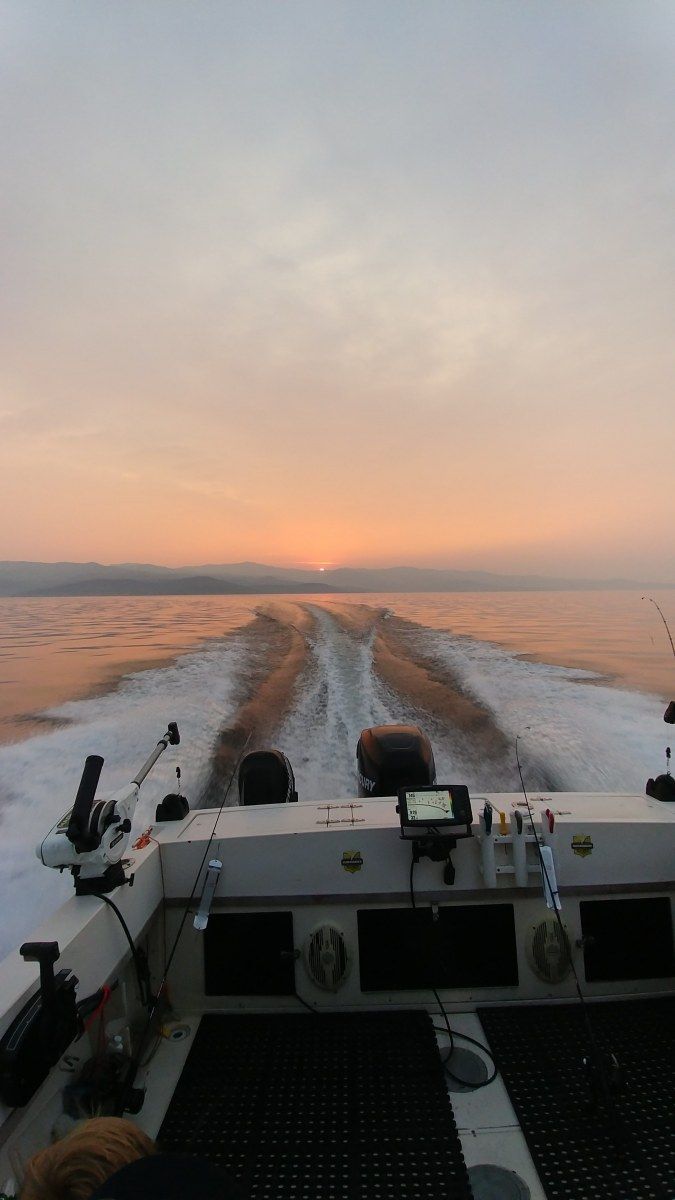 A boat is going through the water at sunset.