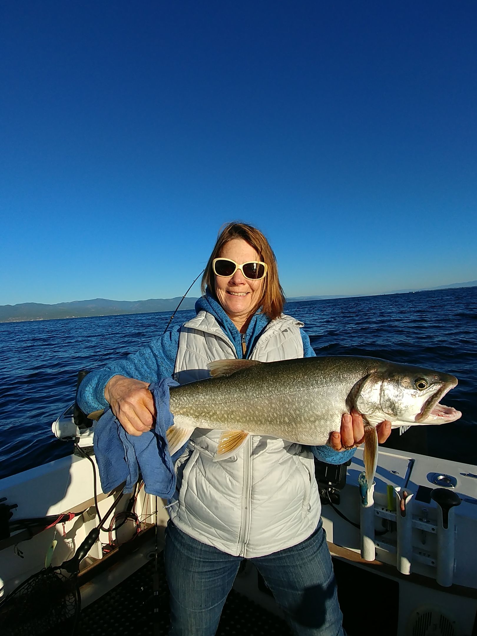 A woman is holding a large fish on a boat.