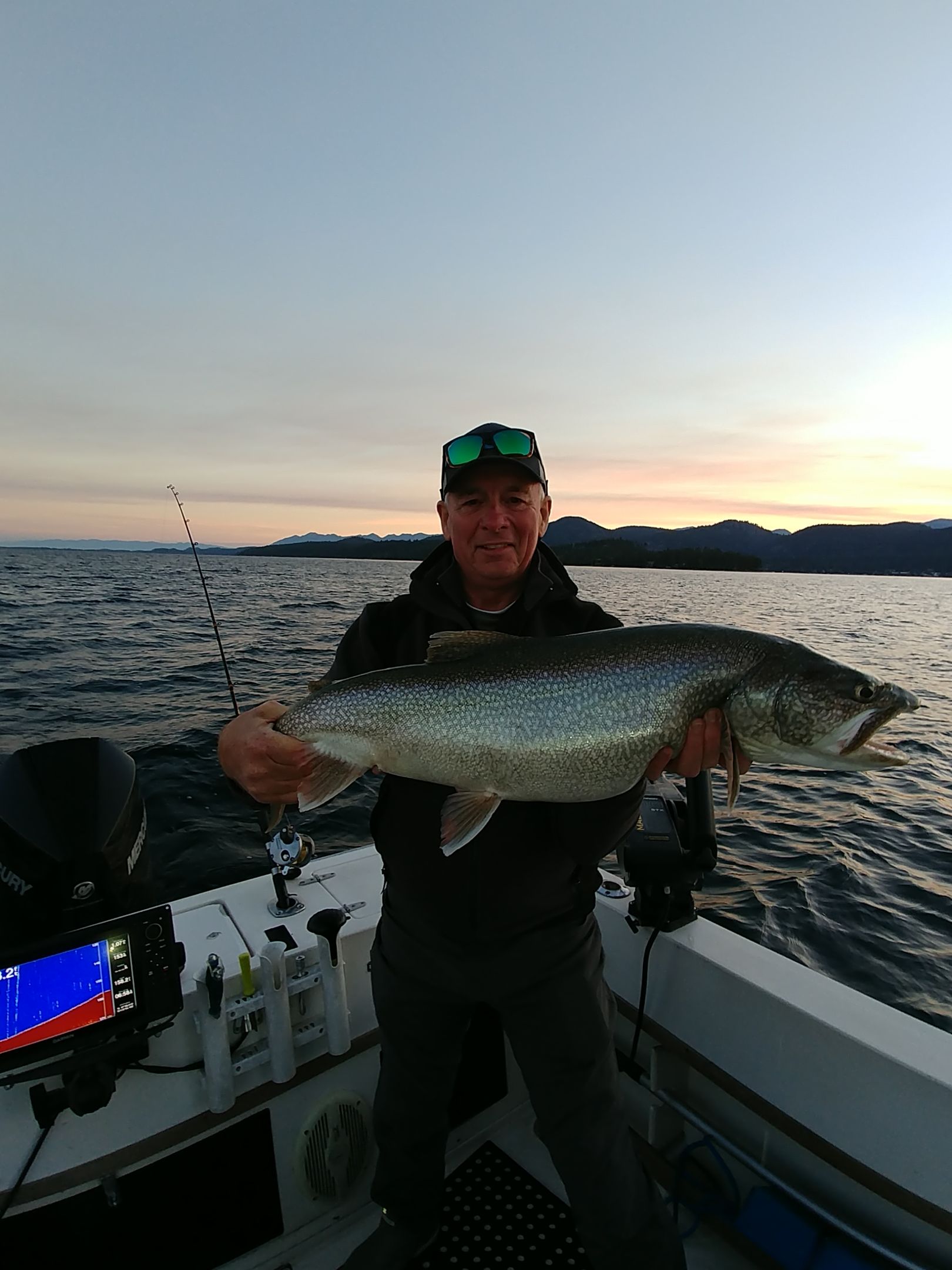 A man is holding a large fish on a boat.