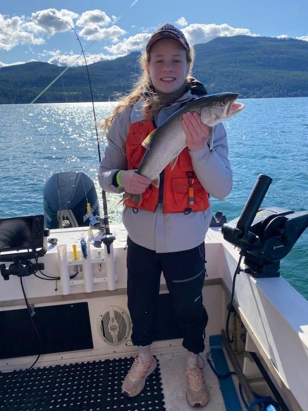 A woman is standing on a boat holding a fish.
