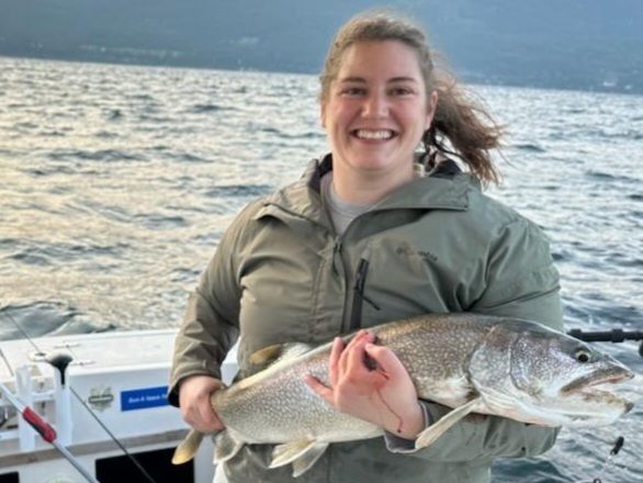 A woman is holding a large fish on a boat