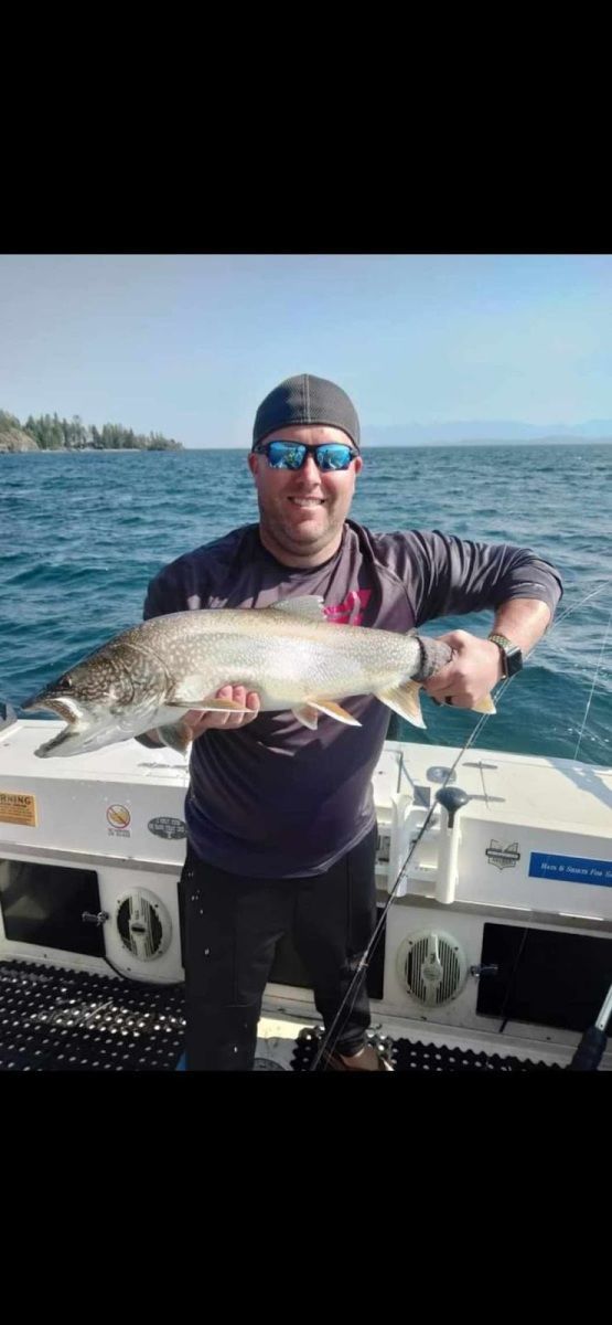 A man is holding a large fish on a boat in the water.