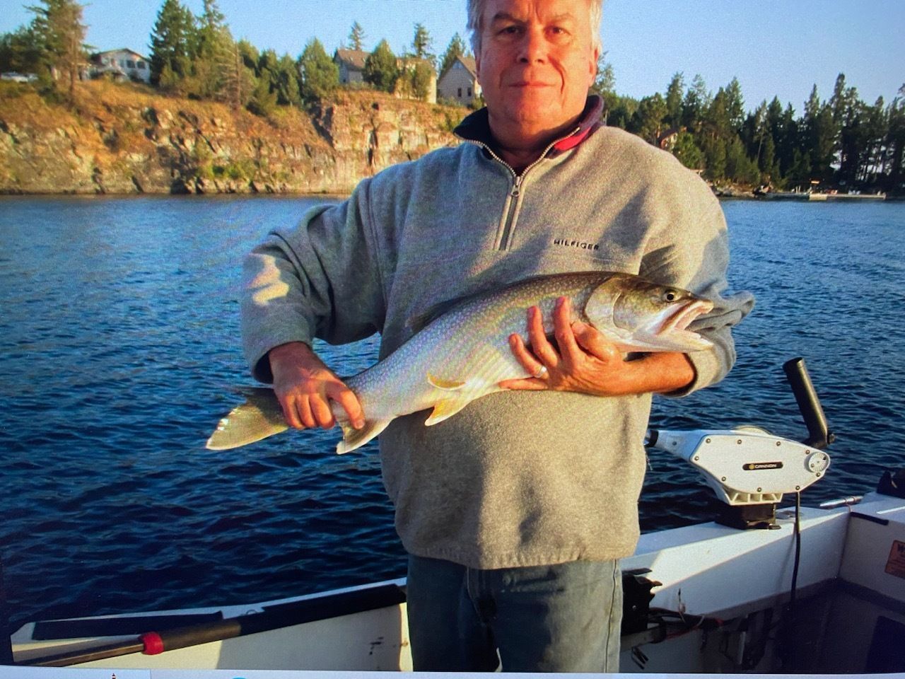 A man on a boat holding a large fish