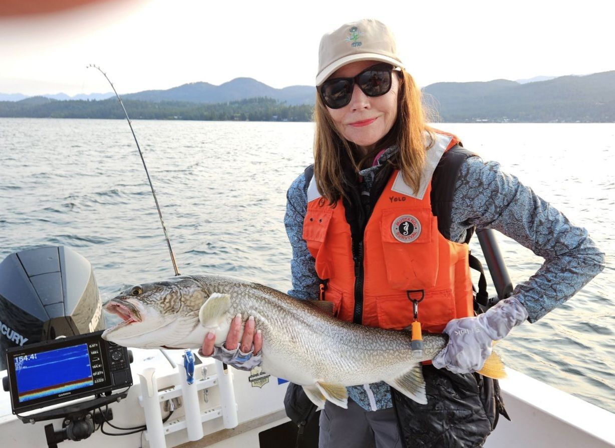 A woman is holding a large fish on a boat.