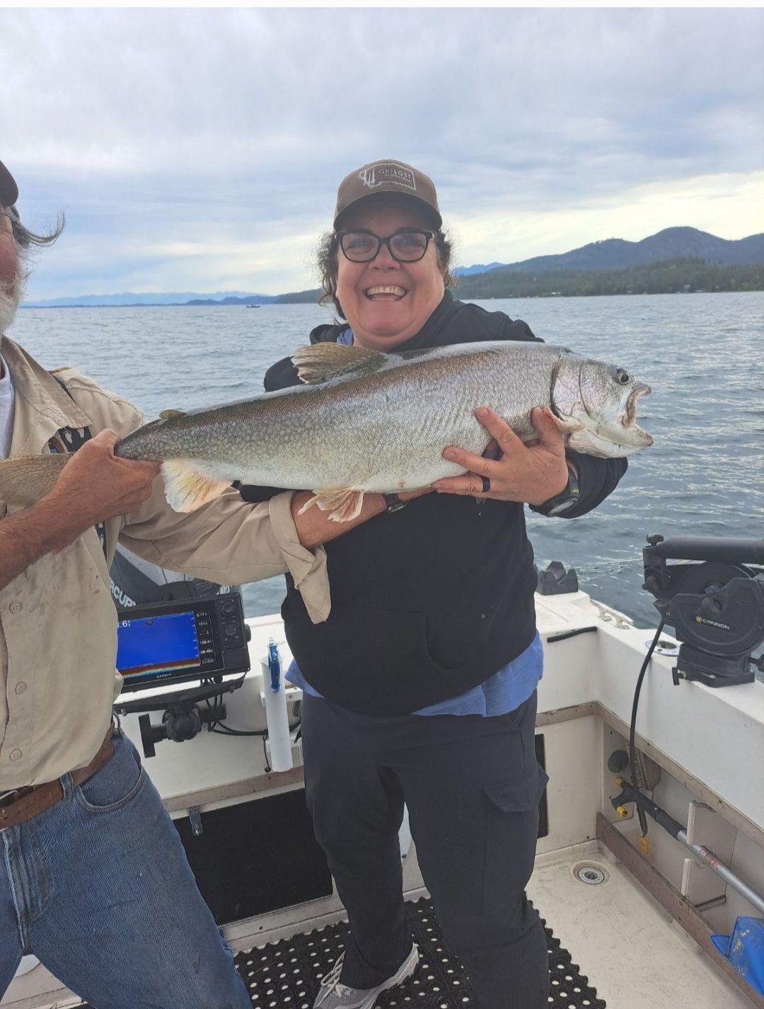 A man and woman holding a large fish on a boat