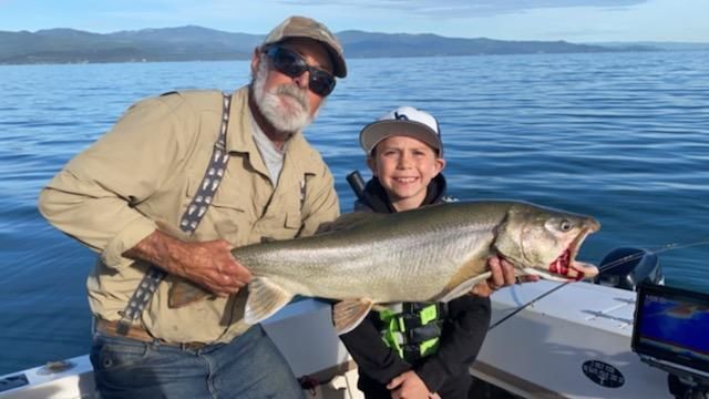 A man and a boy are holding a large fish on a boat.