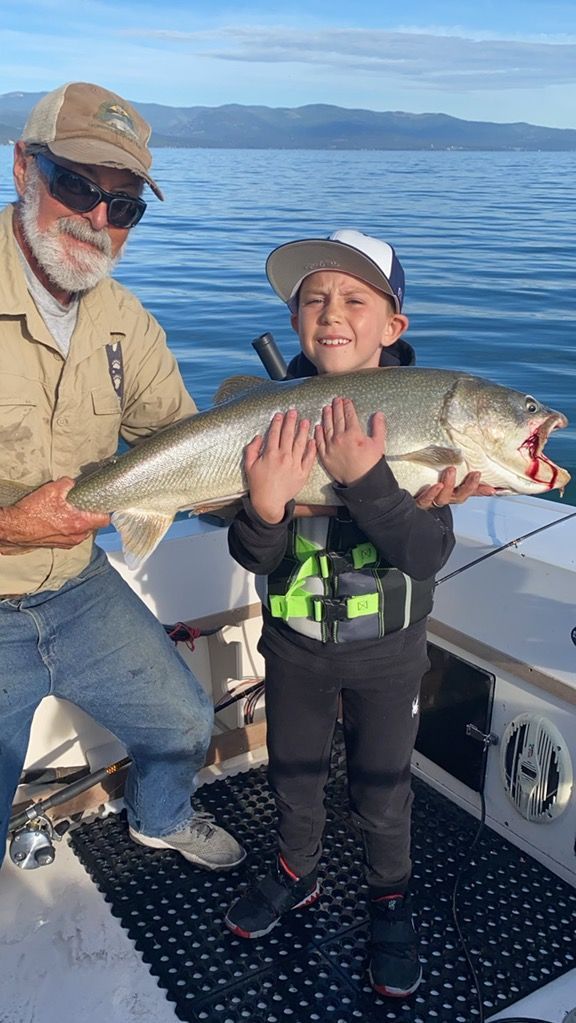 A man and a boy are holding a large fish on a boat.