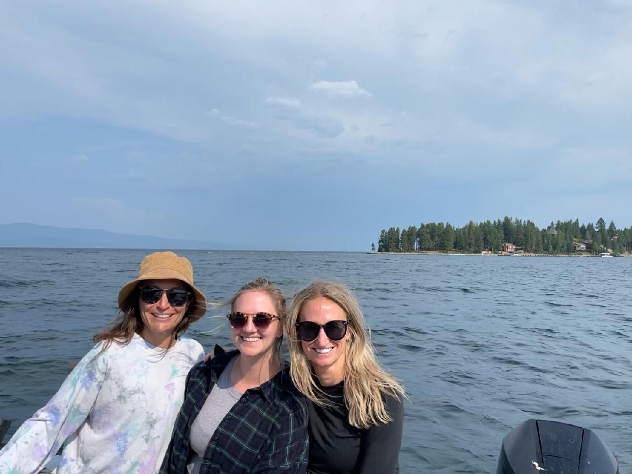 Three women are posing for a picture on a boat in the water.