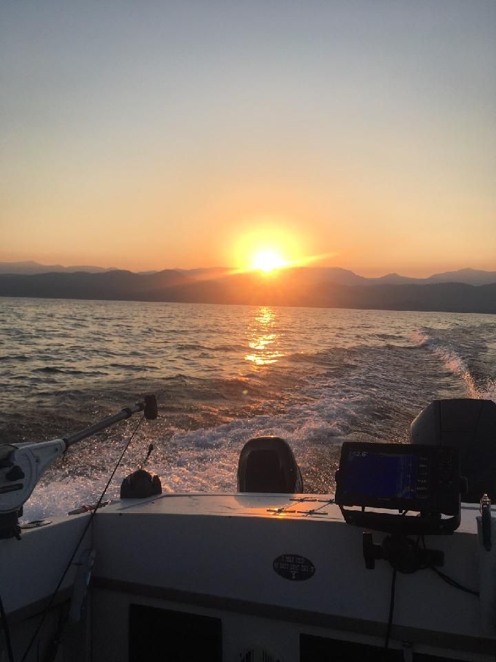The sun is setting over the ocean behind a boat